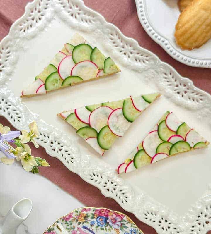 Top view of cucumber an radish tea sandwiches on a rectangular tea serving platter.