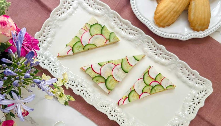 Top view of cucumber an radish tea sandwiches on a rectangular tea serving platter.