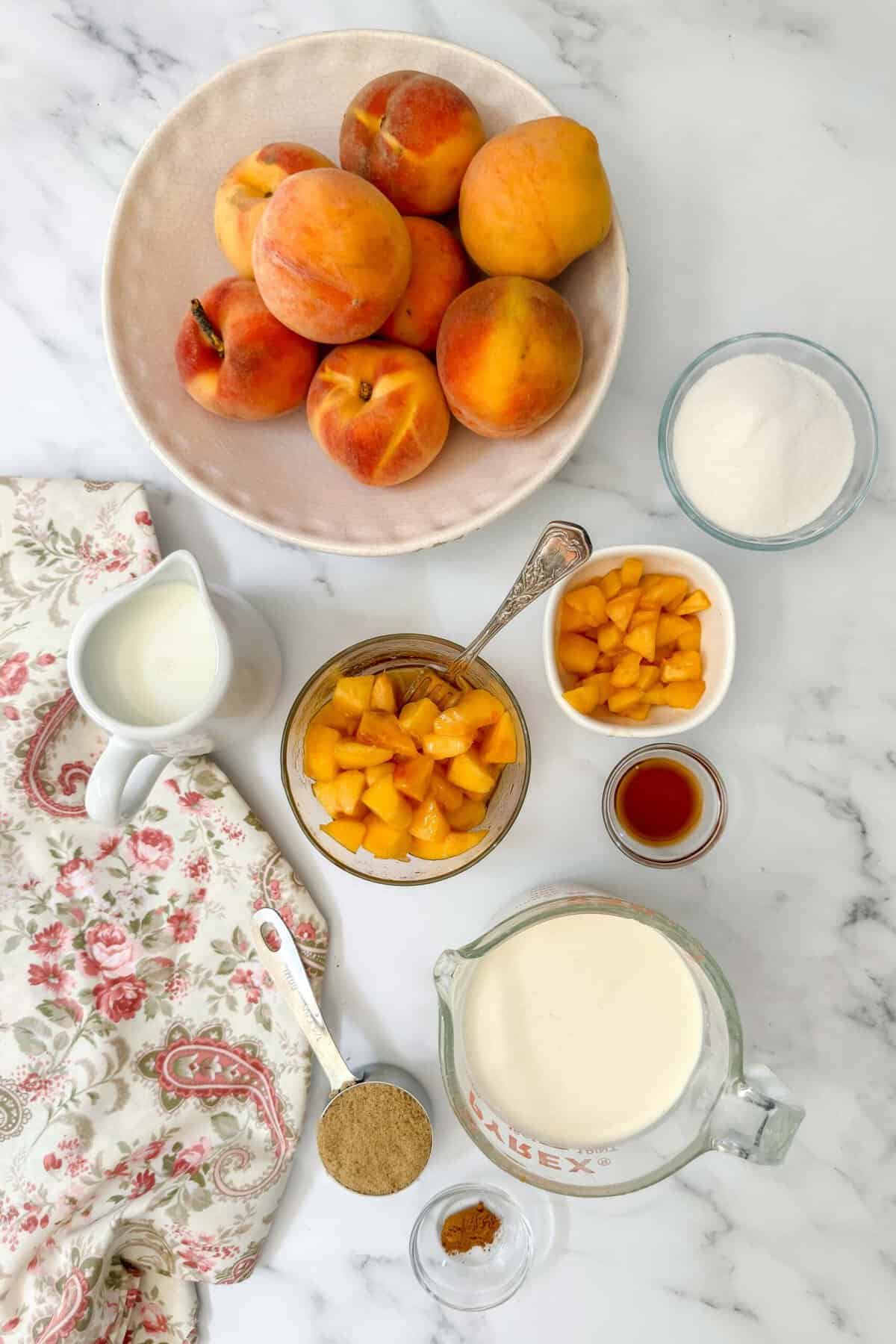 Top view of peach ice cream ingredients on a white marble background.