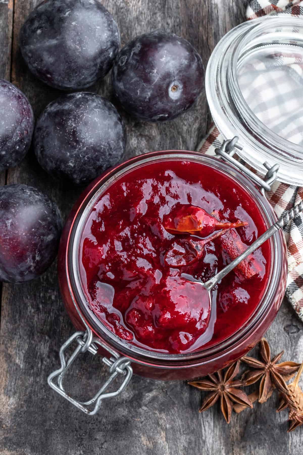 Top view of plum chutney in a glass jar with Italian plums.