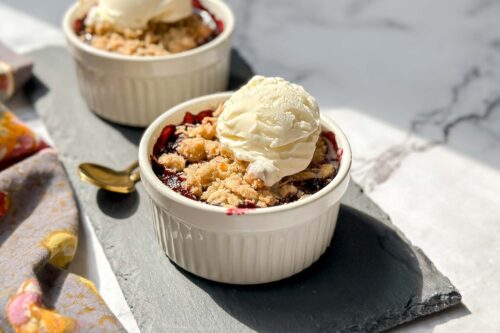 Side view of Individual Berry Crisps in a white ramekin on a black slate board.
