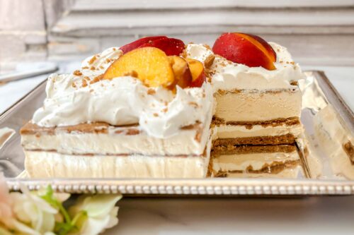 Side horizontal view of peach icebox cake with a serving missing.