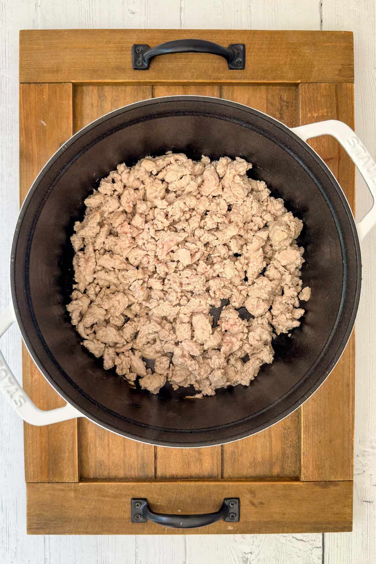 Ground turkey browning in a black pot with white handles.