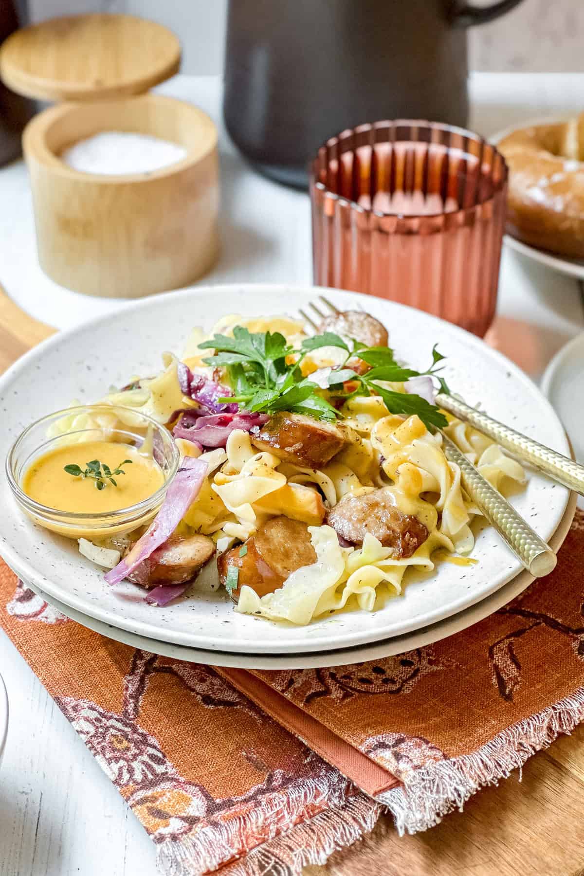 Serving of German cabbage and noodles with mustard sauce on a plate with utensils.