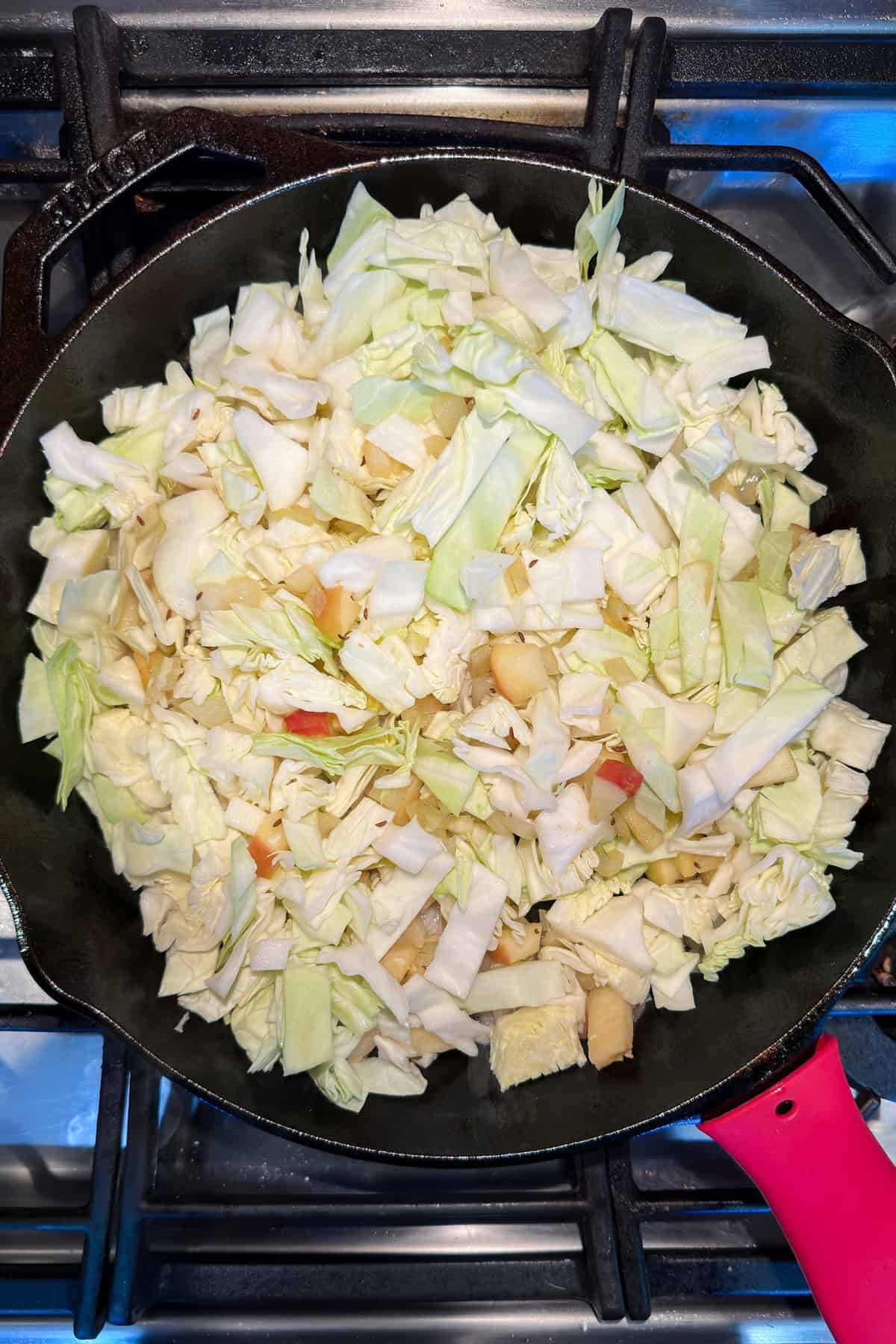 Sauteing chopped cabbage in a cast iron skillet.
