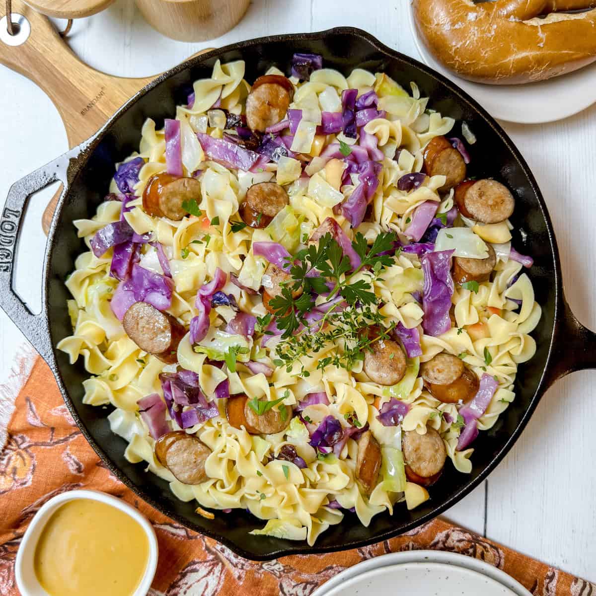 German cabbage and noodles with bratwurst and apples in a cast iron skillet ready for serving.