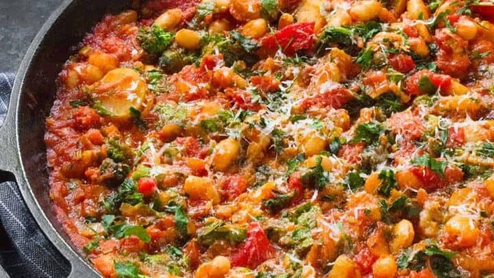 Side view of Mediterranean Diet friendly white bean skillet in a black cast iron skillet.
