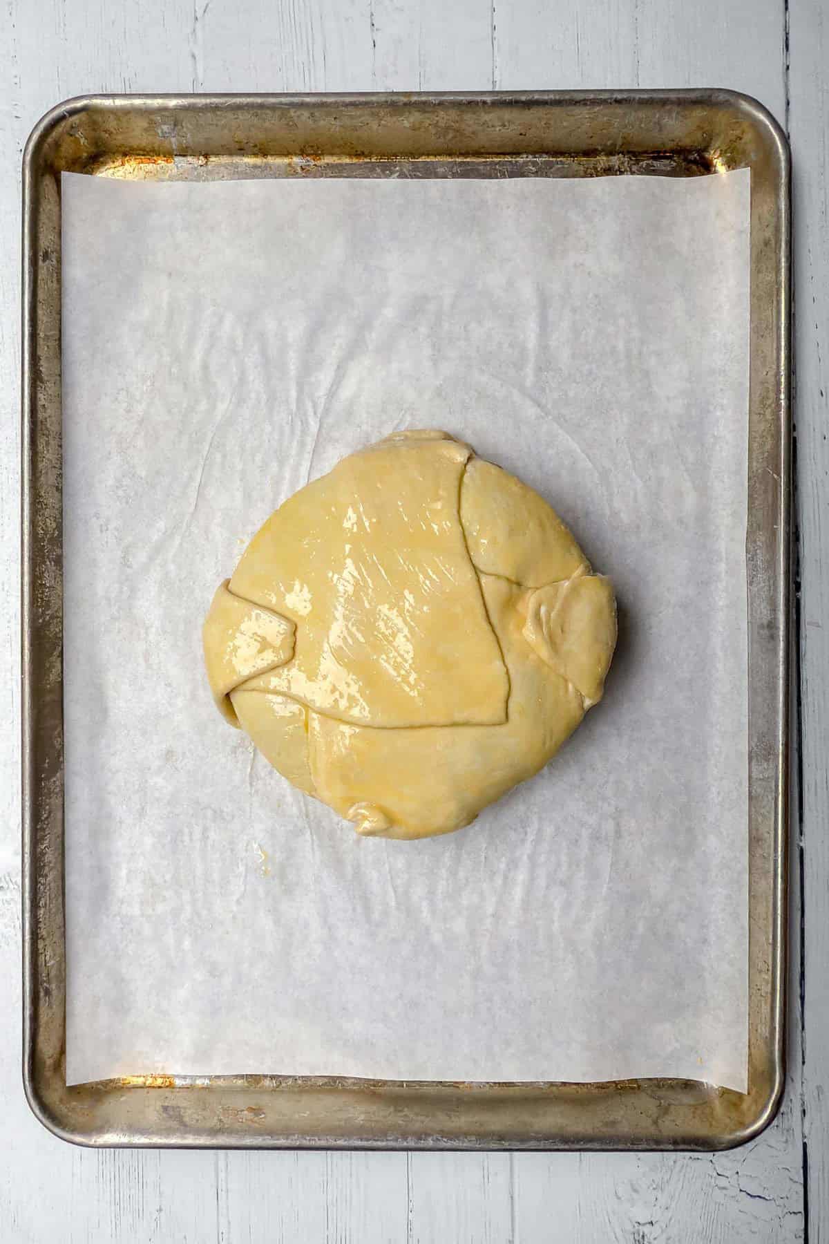 Puff pastry wrapped Brie wheel on a parchment lined sheet for baking.