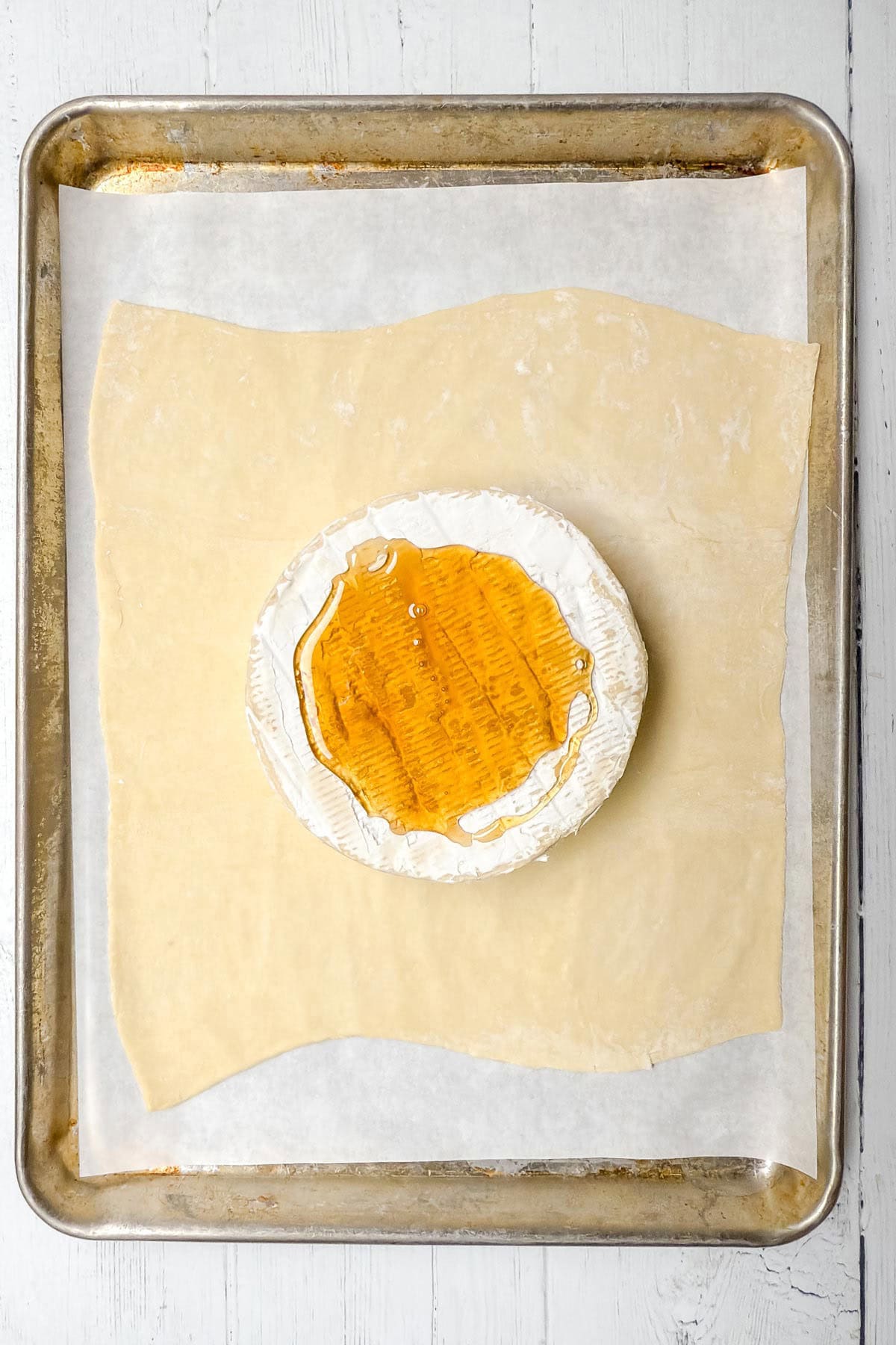 Baked Brie wheel on sheet of puff pastry, scored, and topped with honey.