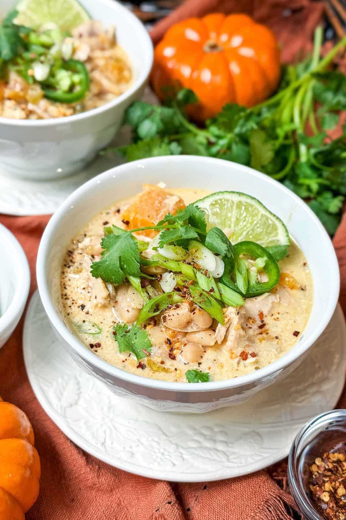 Close-up of creamy butternut white chicken chili topped with cilantro, lime, and sliced jalape&ntilde;o