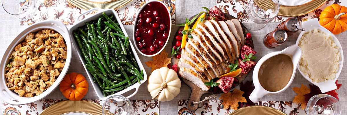 Thanksgiving dinner with sliced turkey breast, cranberry sauce, green beans, mashed potatoes and more.