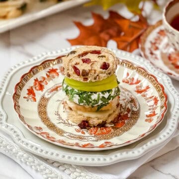 Apple Turkey Tea Sandwich with cranberry bread, slices of apple and herbed goat cheese on a Spode plate for serving afternoon tea.