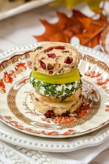 Apple Turkey Tea Sandwich with cranberry bread, slices of apple and herbed goat cheese on a Spode plate for serving afternoon tea.