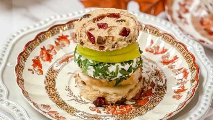 Apple Turkey Tea Sandwich with cranberry bread, slices of apple and herbed goat cheese on a Spode plate for serving afternoon tea.