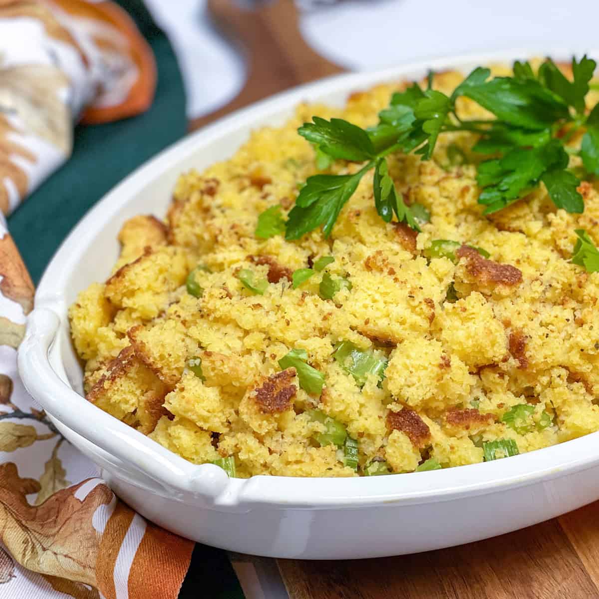 Baked cornbread dressing (cornbread stuffing) in an oval casserole dish and topped with fresh parsley.