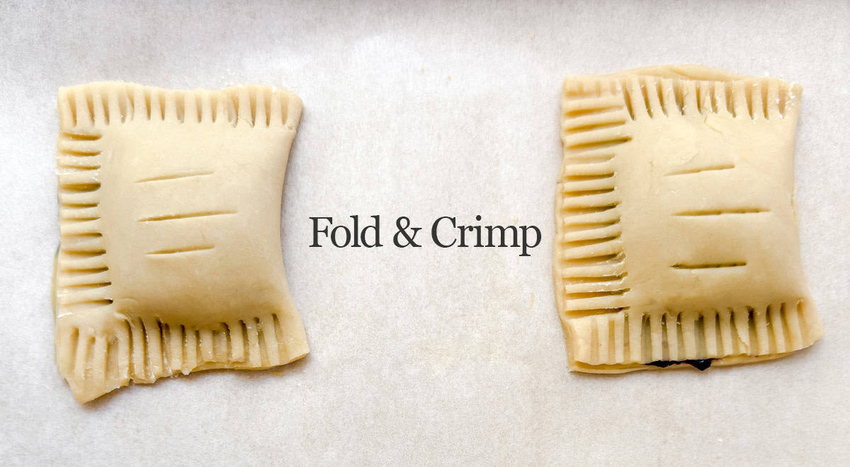 Two square blueberry hand pies on parchment paper, each with forked crimped edges and slits on top; the text "Fold & Crimp" is centered between them.