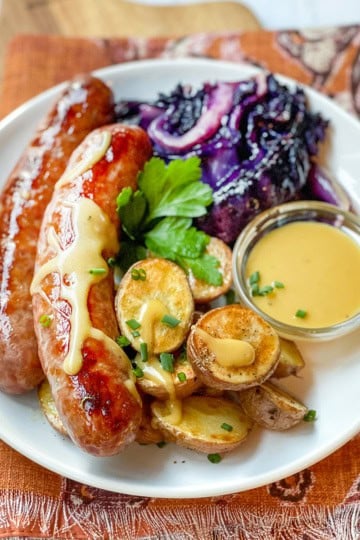 Sheet Pan bratwurst, cabbage, and potatoes with mustard sauce on the side.