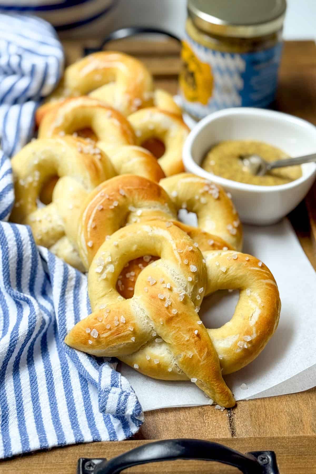 Stack of homemade soft pretzels with grainy mustard in the background.