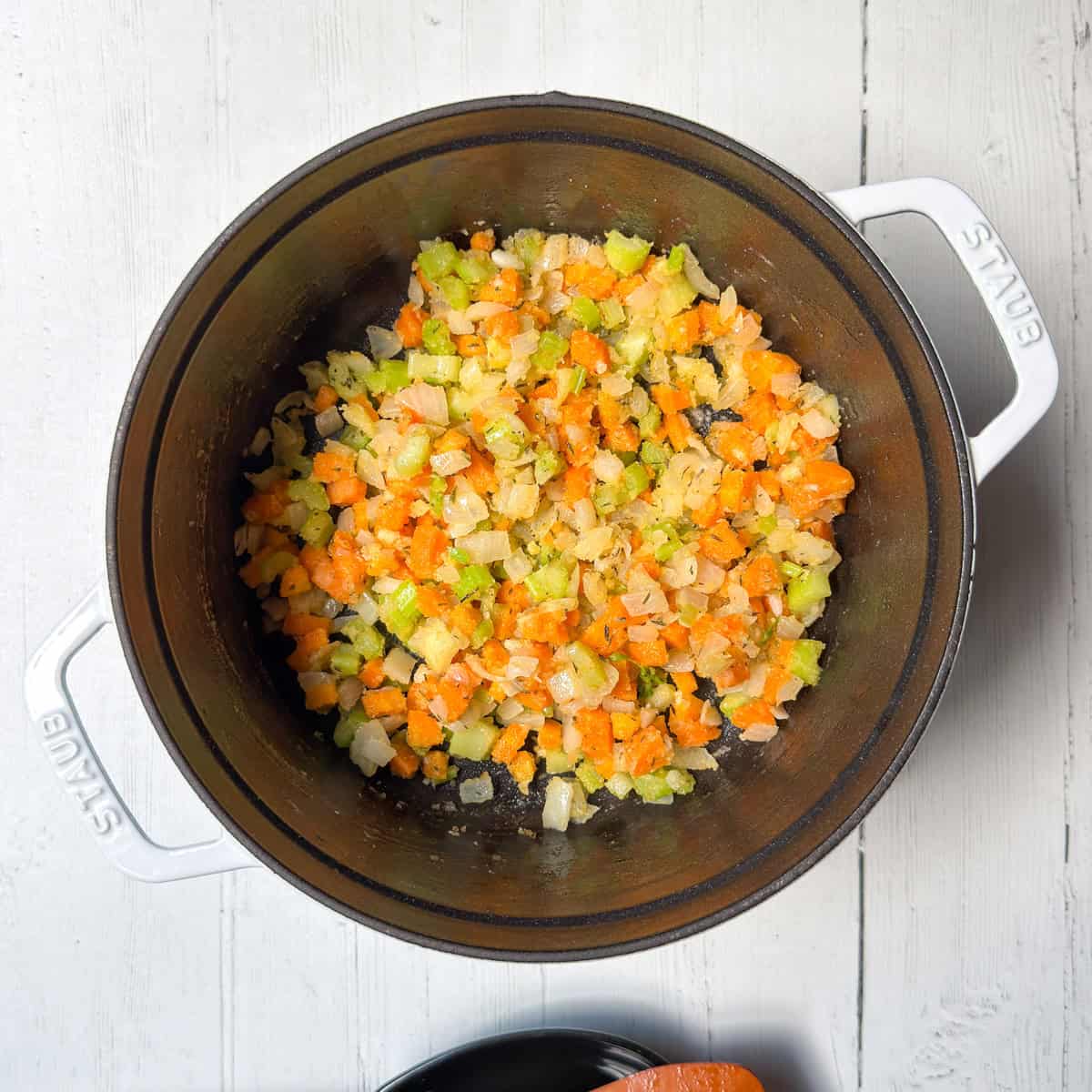 Adding flour to sautéed vegetables to thicken the soup.