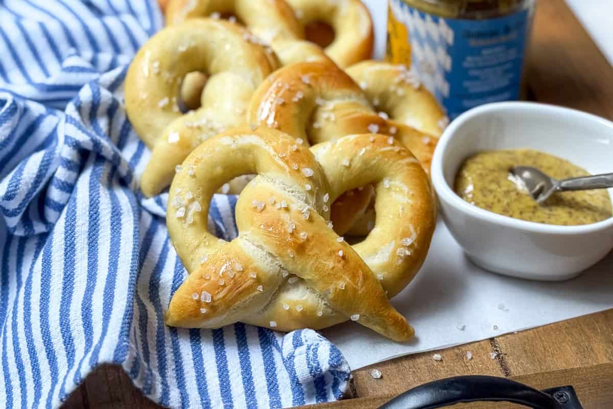 Six homemade pretzels lined up on a cloth and ready for serving.