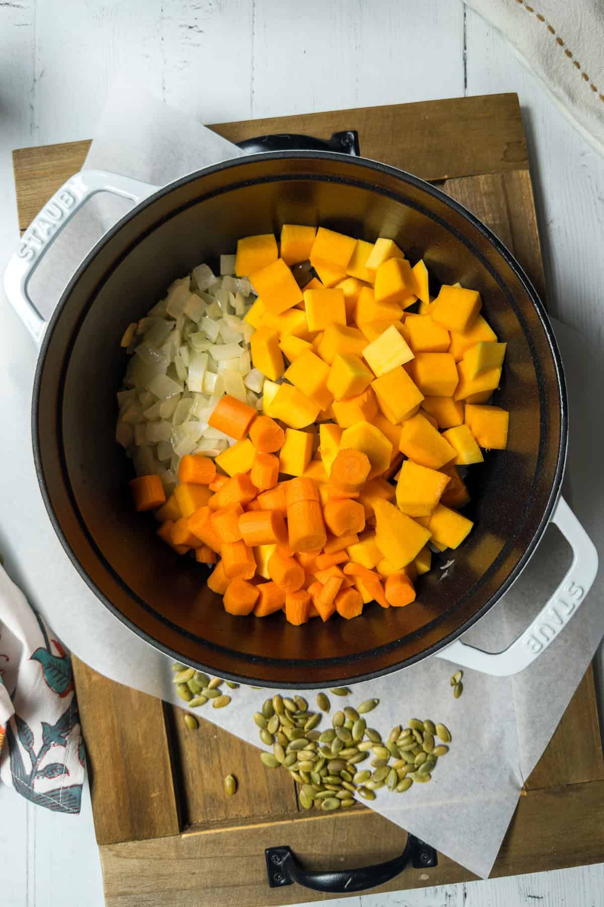 Onion, carrots, and butternut squash sautéing in a Dutch oven.