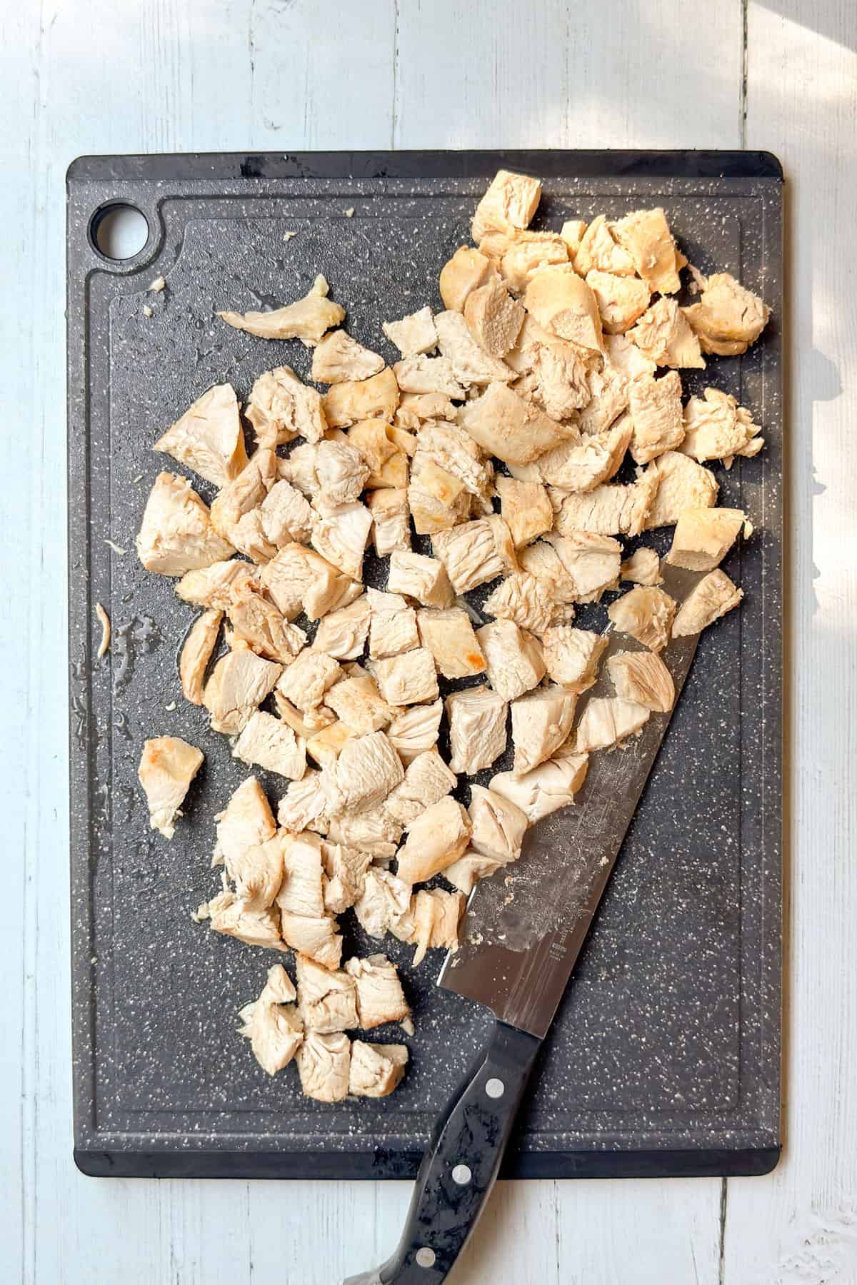 Cooked chicken breasts chopped into bite-sized pieces on a cutting board.
