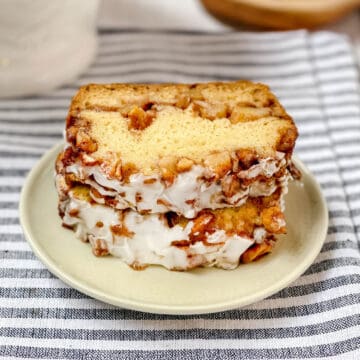 Two slices of apple fritter bread on a white plate with an apple layer visible on the top slice.