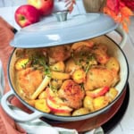 Chicken thighs roasting with root vegetables and potatoes in a braiser with creamy cider sauce.