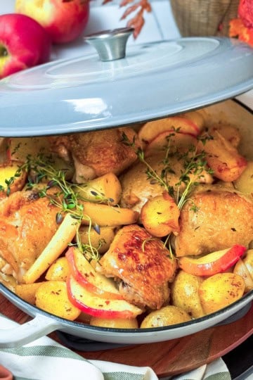 Baked Cider Braised Chicken with root vegetable and apple slices ready to serve.