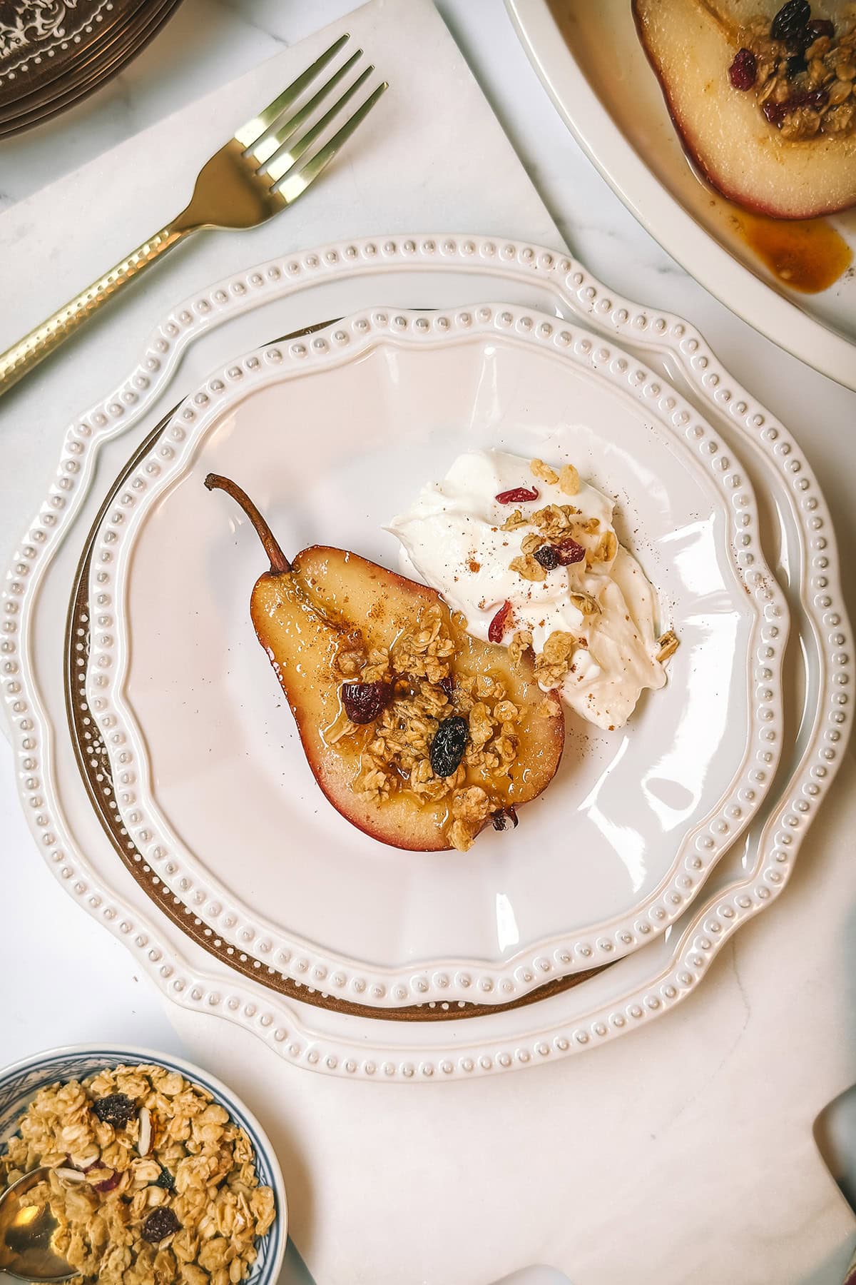 Baked pears on a scalloped plate for serving with Greek yogurt and granola on the side.