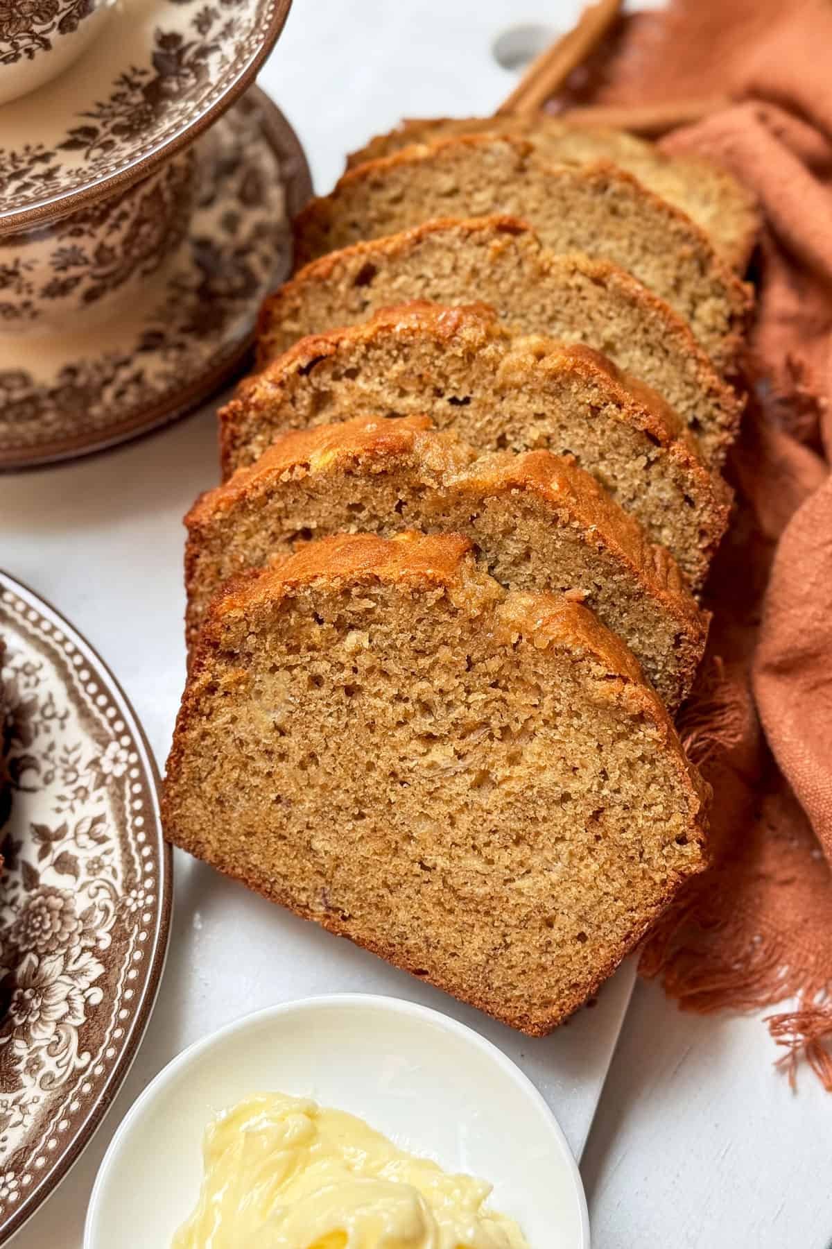 Sliced banana bread with plated servings and honey butter.