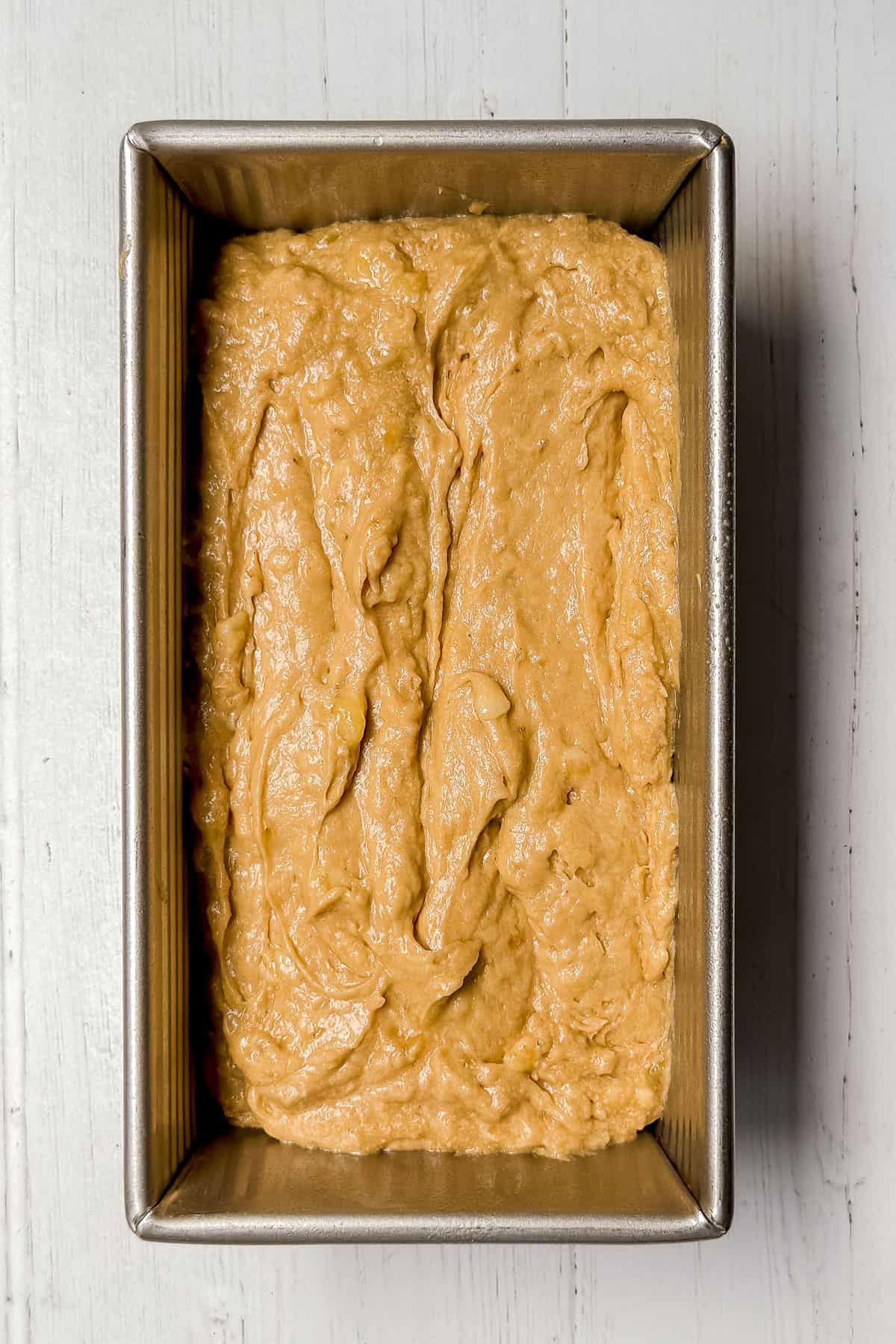Unbaked banana bread batter in a stainless loaf pan ready for baking.