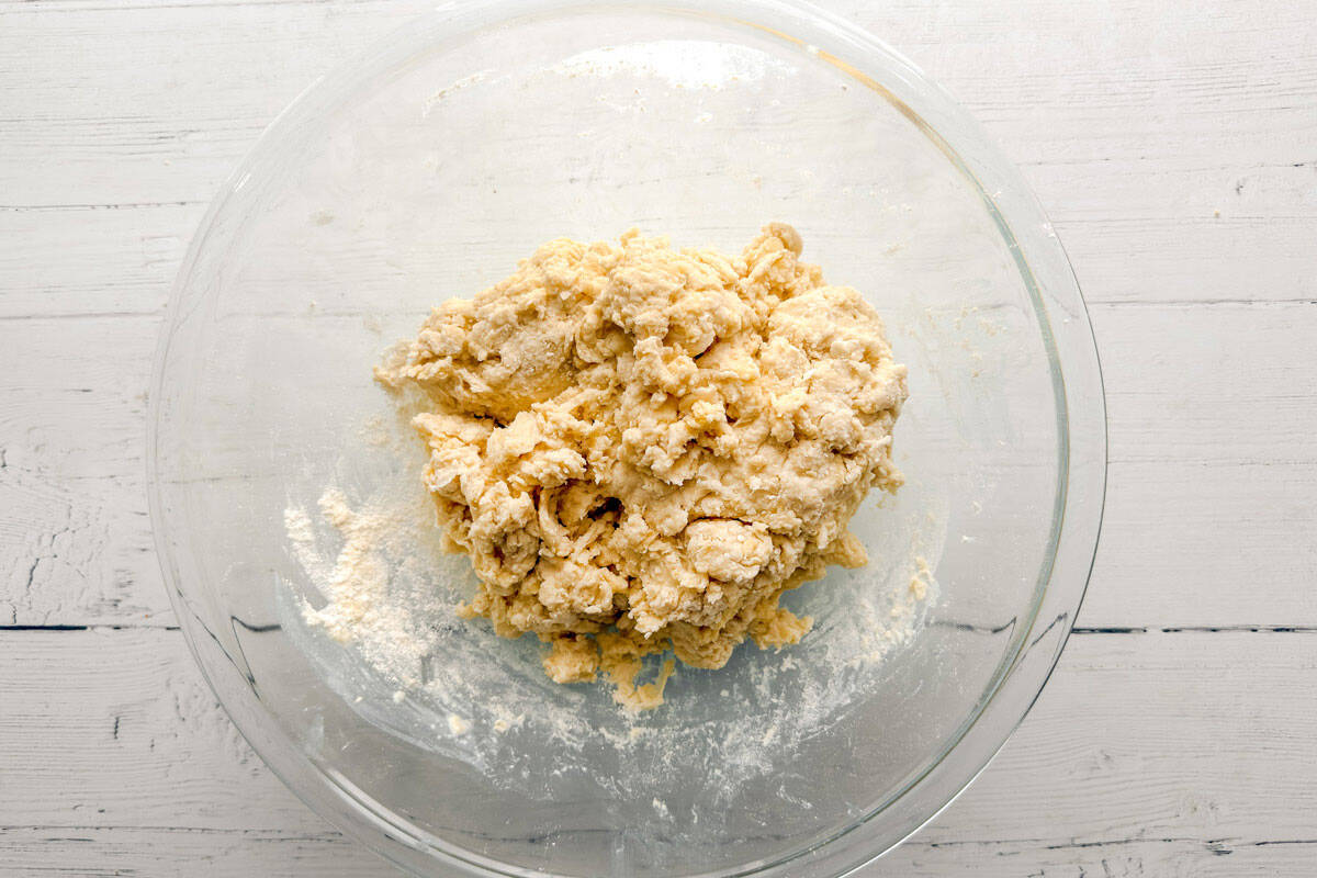 Rough scone dough coming together in a mixing bowl.