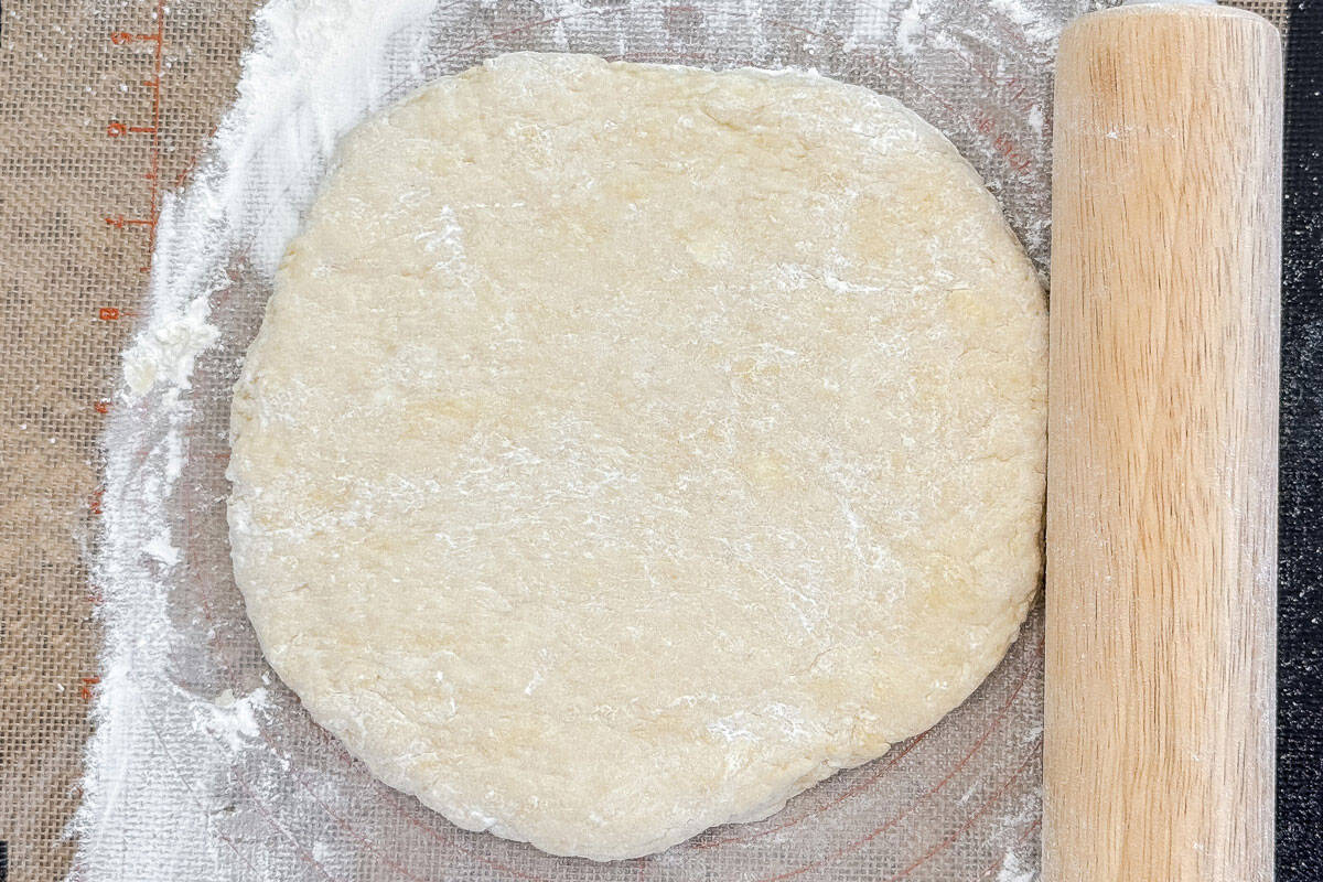Rolled out scone dough on floured surface with rolling pin.
