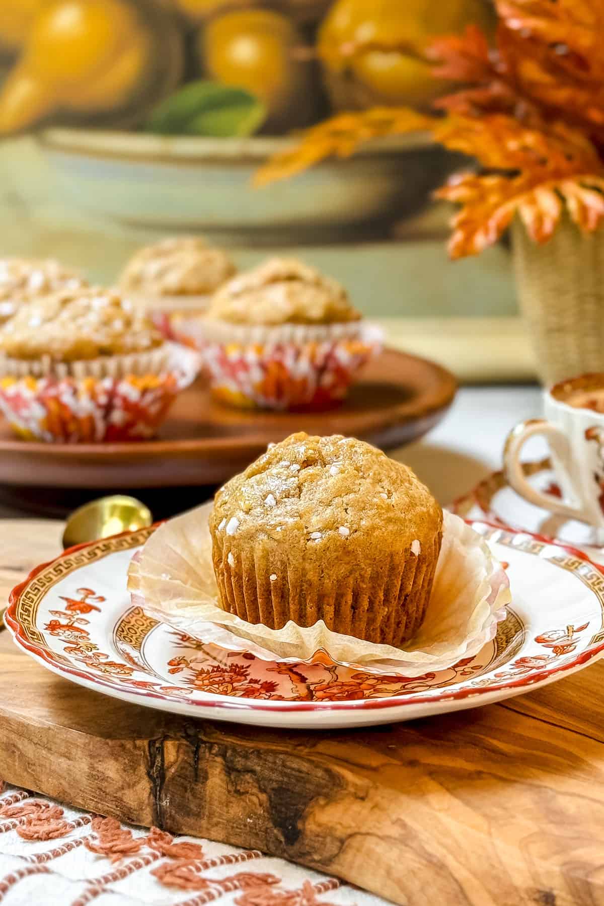 Healthy Apple Muffins on a plate with paper lining fanned out below and more muffins in the background.