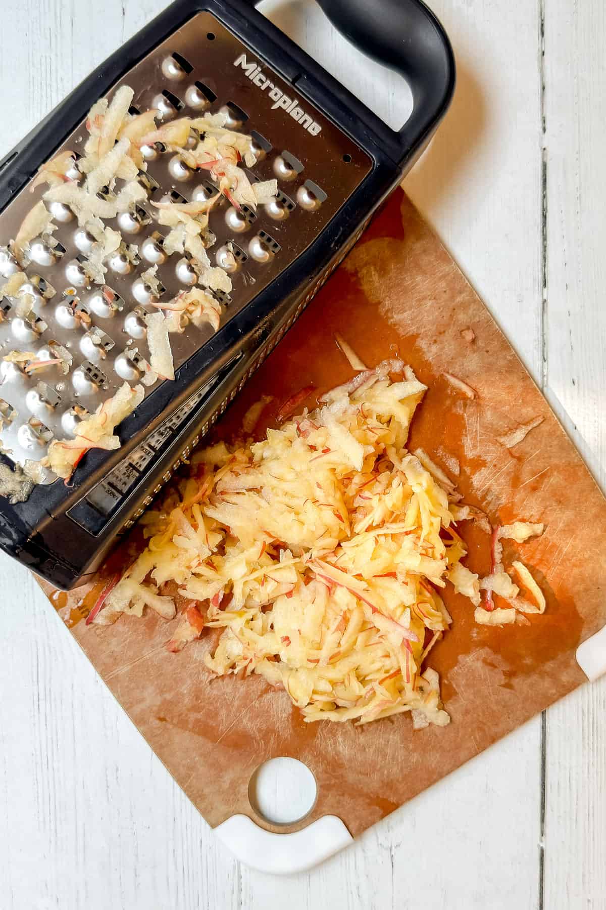 Fresh apple shredded on a box grater for apple muffin batter.
