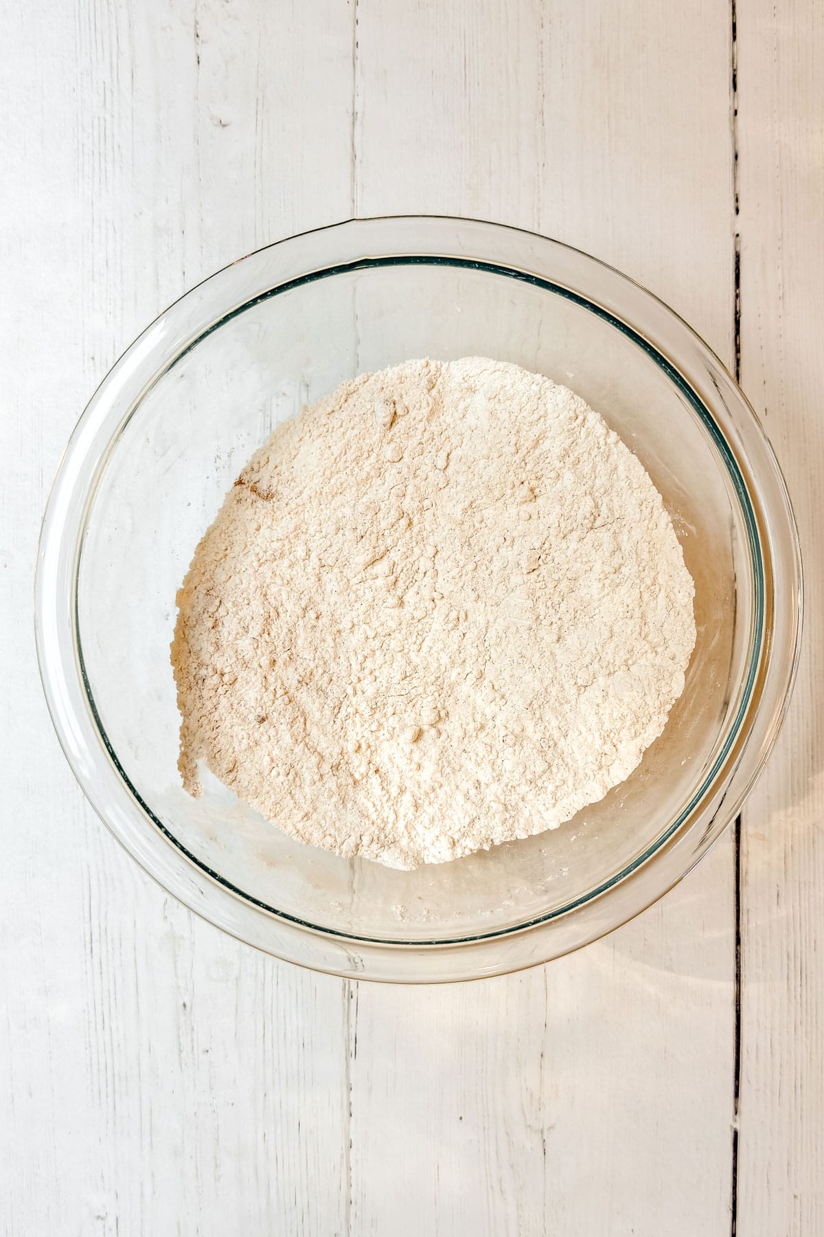 Glass bowl with flour and spices whisked together for apple muffins.