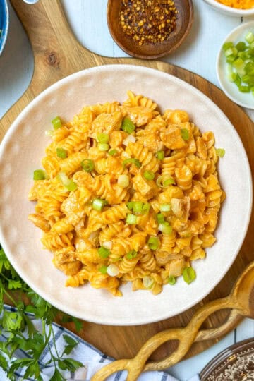 Square overhead photo of Buffalo Chicken Mac and Cheese with salad and garnishes.