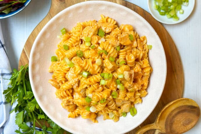 Square overhead photo of Buffalo Chicken Mac and Cheese with salad and garnishes.