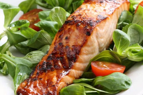 Filet of maple glazed salmon on a bed of watercress greens and sliced cherry tomatoes.