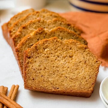 Closeup view of sliced banana bread on a white marble cutting board.