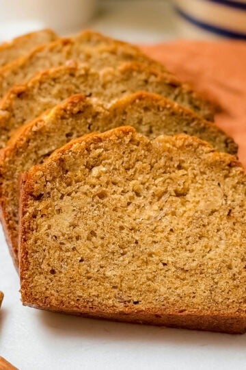 Closeup view of sliced banana bread on a white marble cutting board.