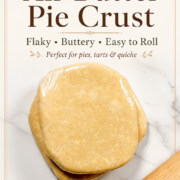 Two chilled all-butter pie crust dough discs wrapped in plastic on a marble surface with a rolling pin, with text reading “All-Butter Pie Crust” and “Flaky, Buttery, Easy to Roll.