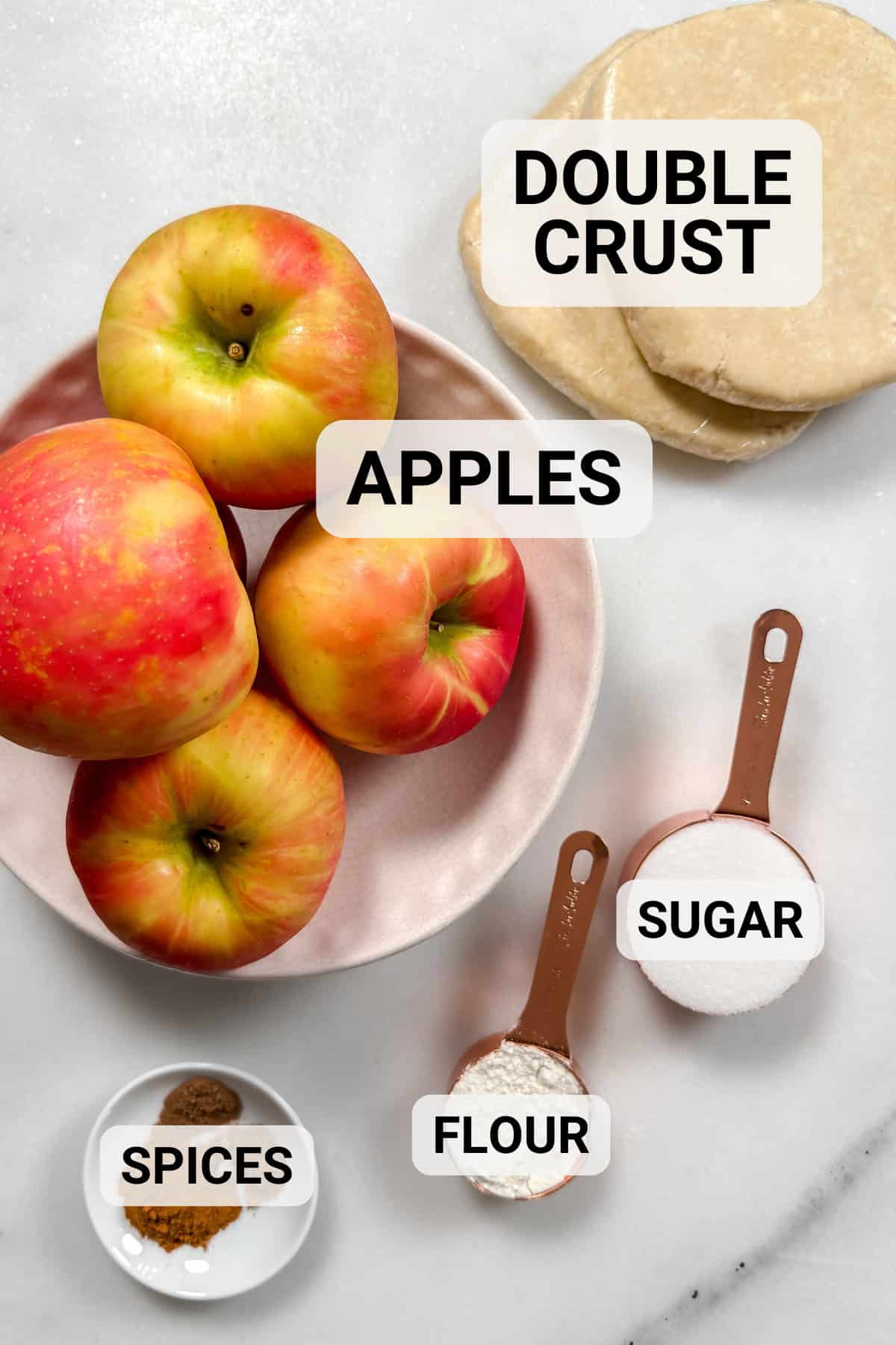 Apple pie ingredients of fresh apples, double crust pastry, sugar, flour, and spices.