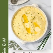 Pinterest image of casserole dish filled with garlic mashed potatoes and a green and white linen on the side.