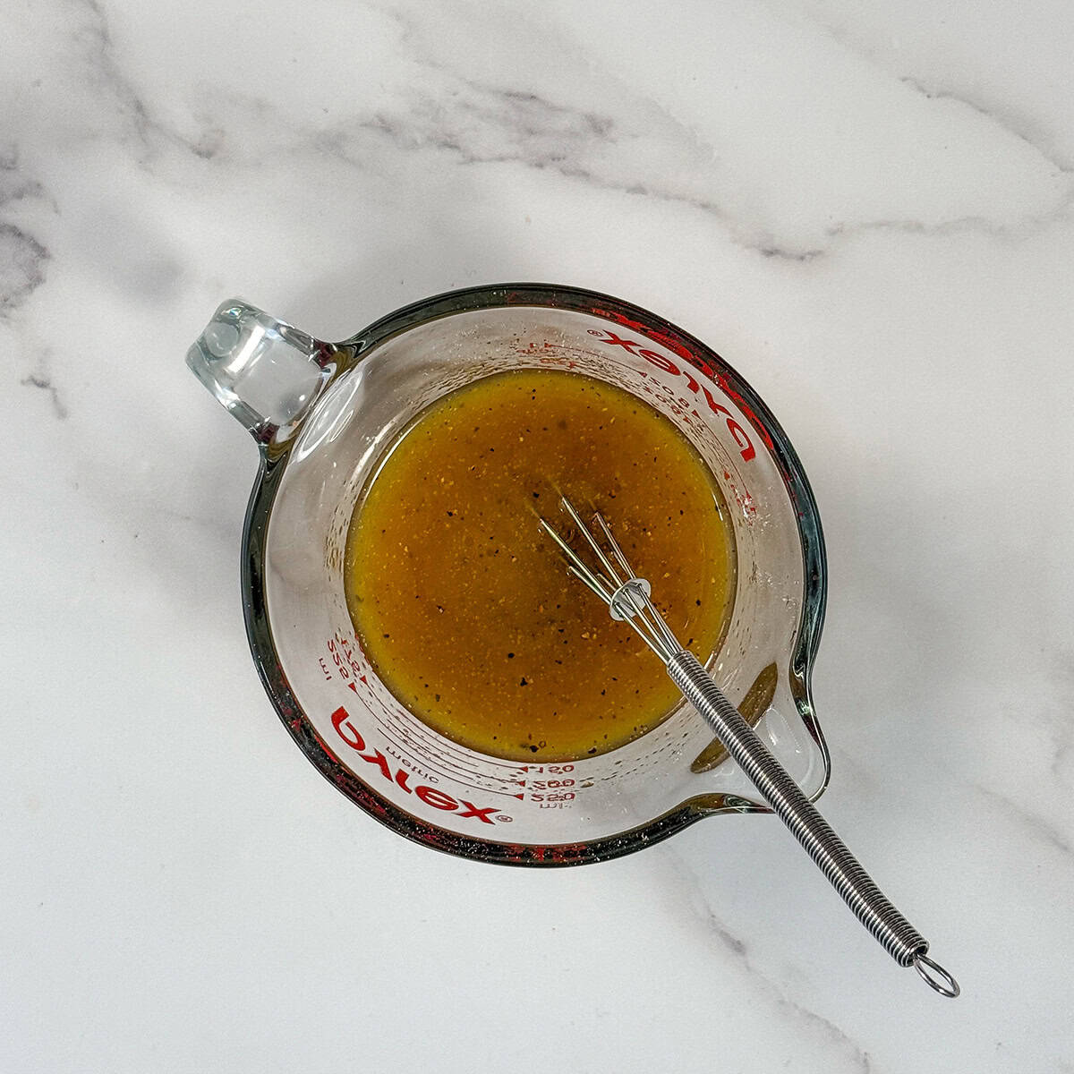 Whisking maple dressing in a small glass measure.