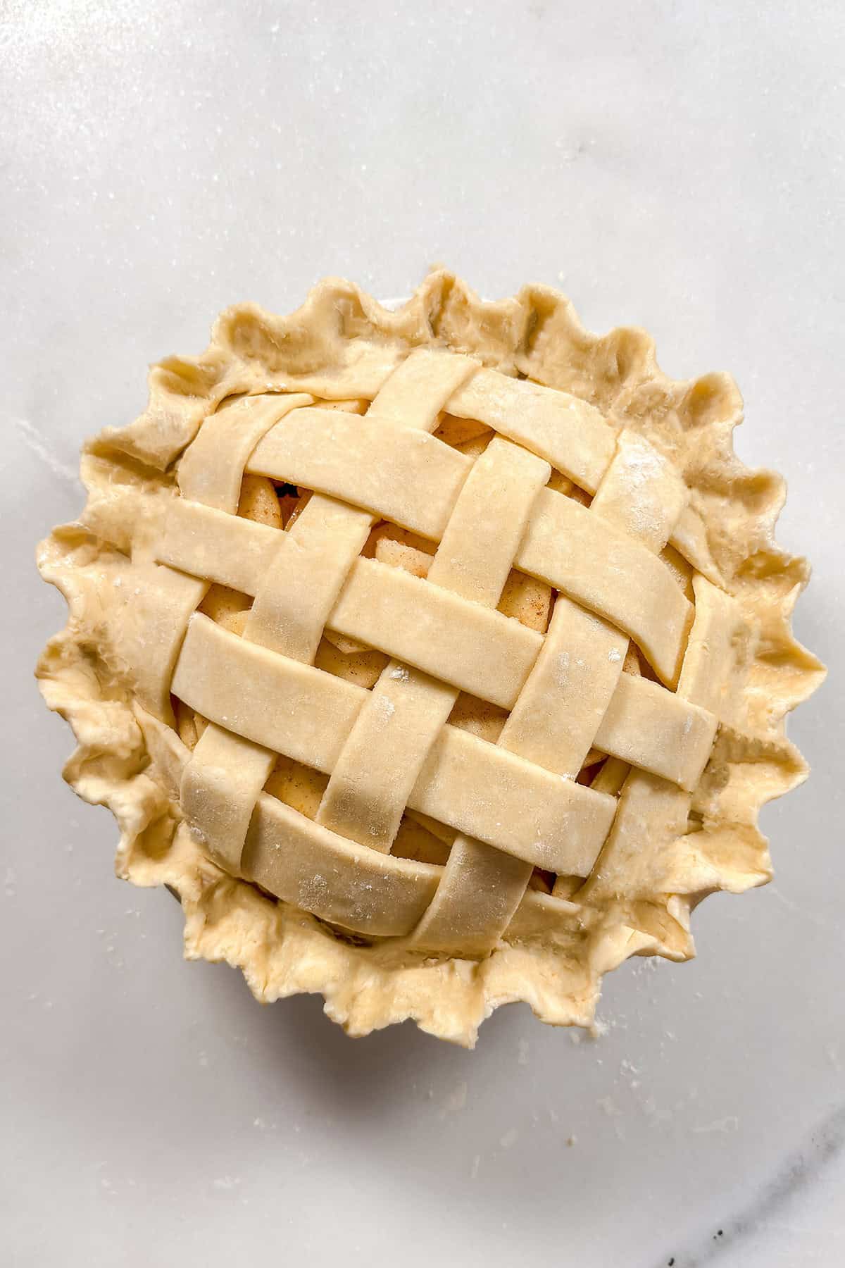 Unbaked apple pie with crimped all butter pie crust edges.