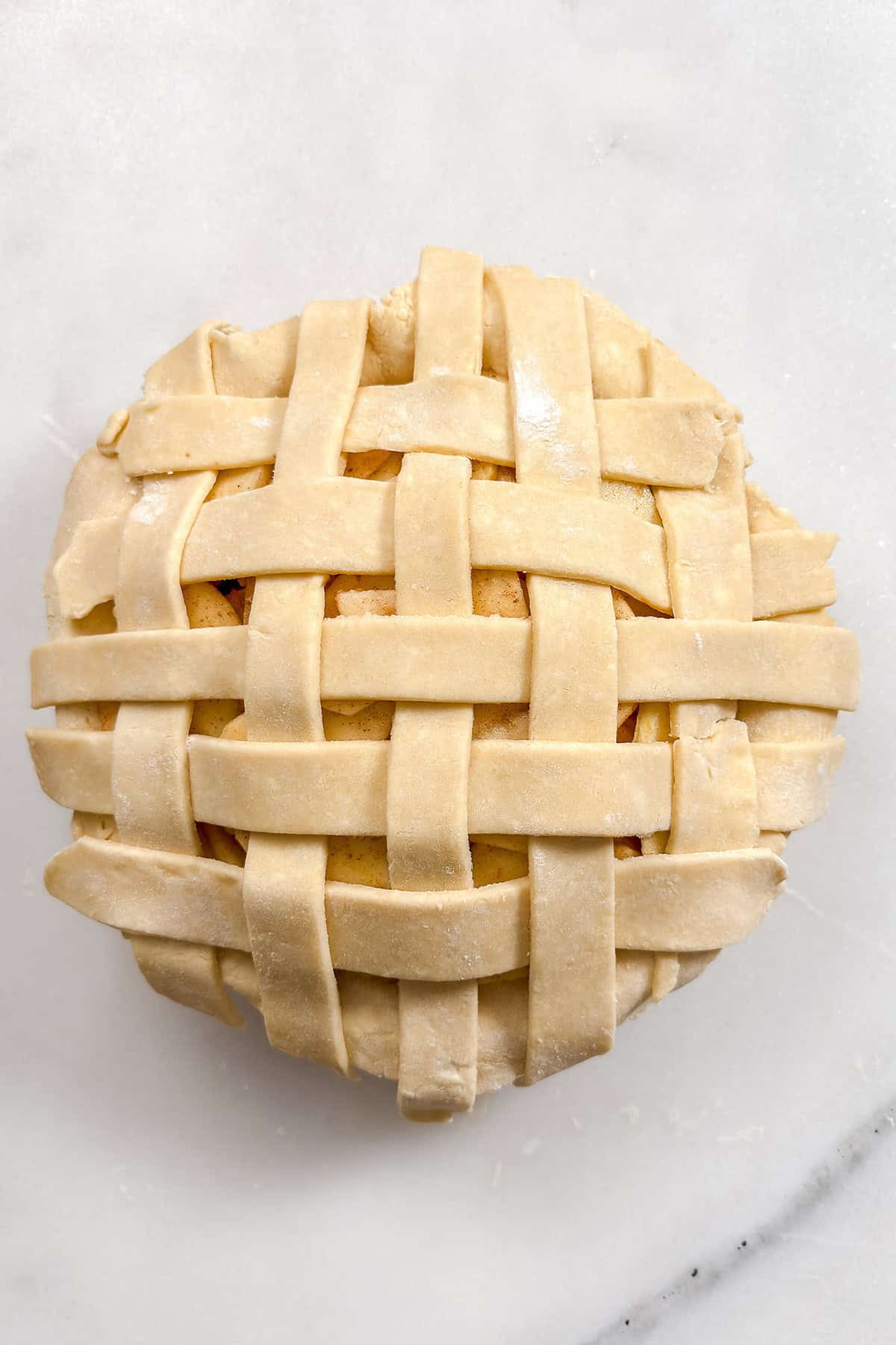 Unbaked lattice all butter pie crust topping sliced apples and ready for baking.