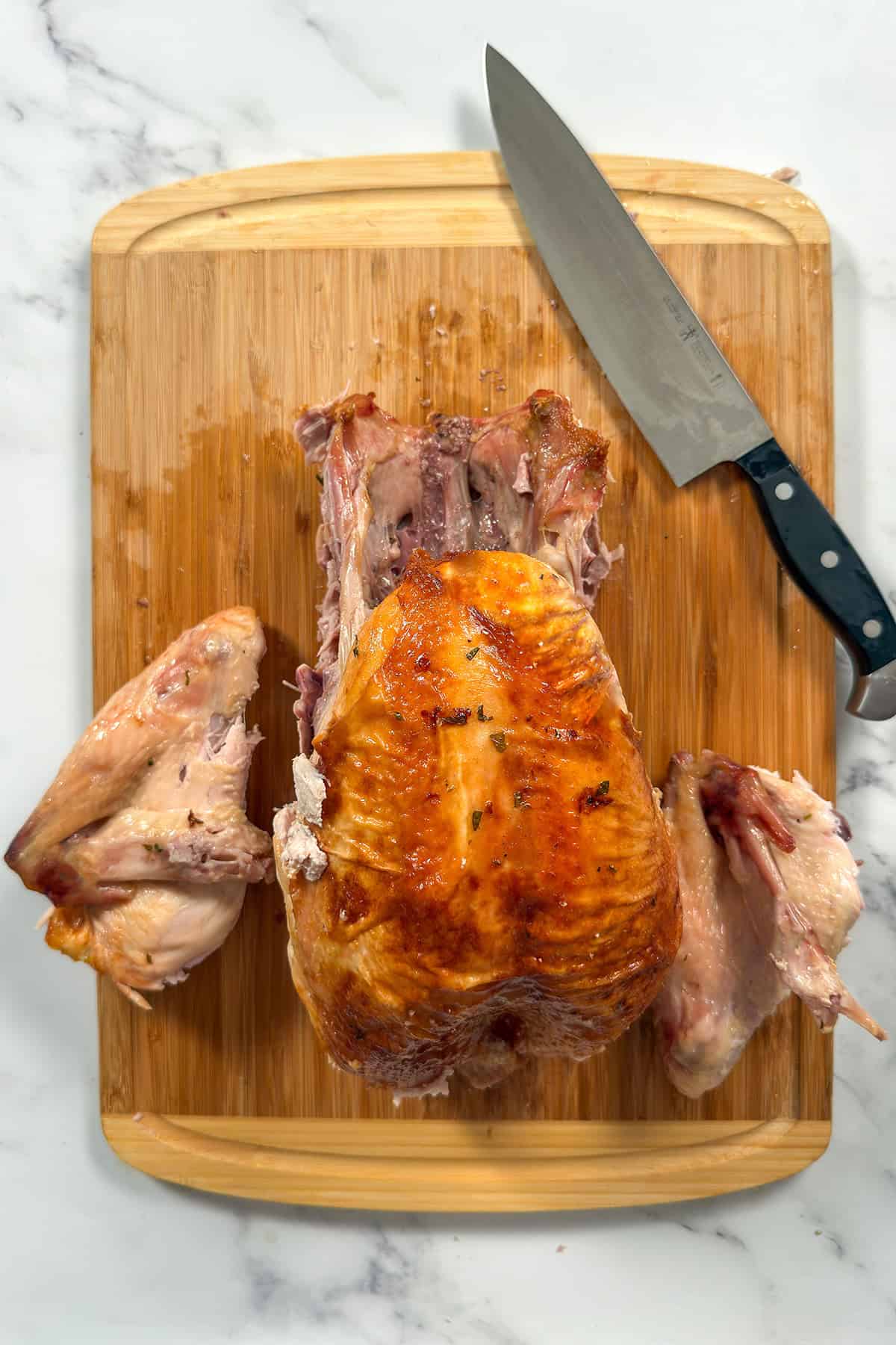 Whole roasted turkey on a bamboo cutting board with both wings removed. 