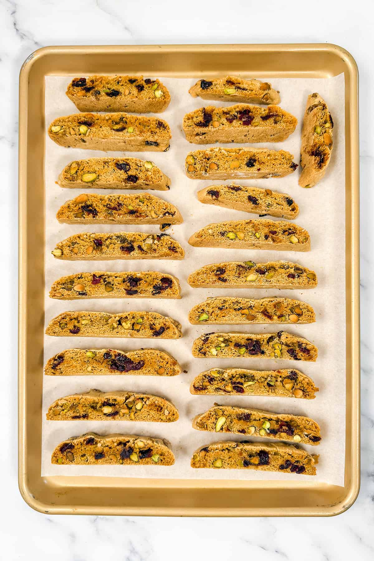 Slices of biscotti on a parchment lined baking sheet ready for final baking.